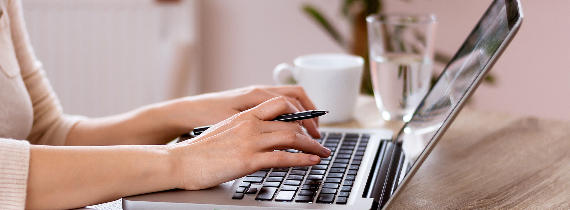 A person typing on a laptop computer with their hands visible above the keyboard.