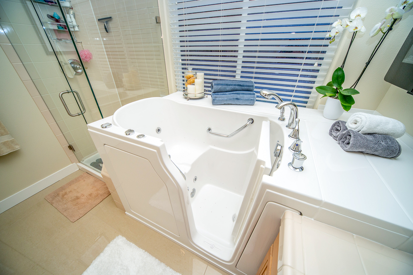 The image shows a modern bathroom interior with a large freestanding bathtub, a walk-in shower, and a sink with a mirror above it.