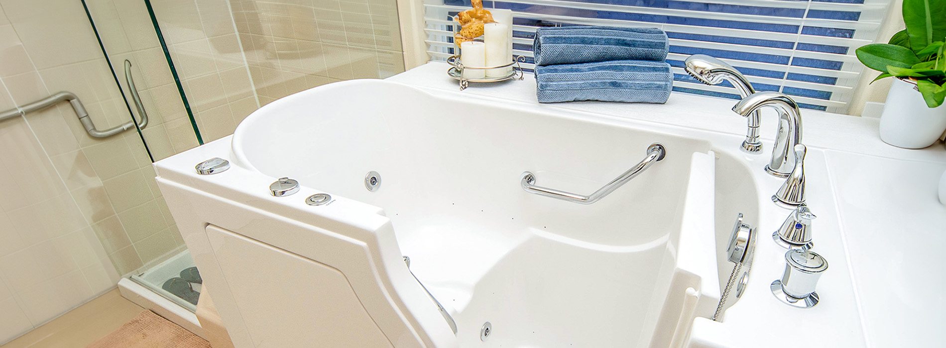 The image shows a modern bathroom with a white bathtub, a blue towel hanging on a rack, and a wooden floor.