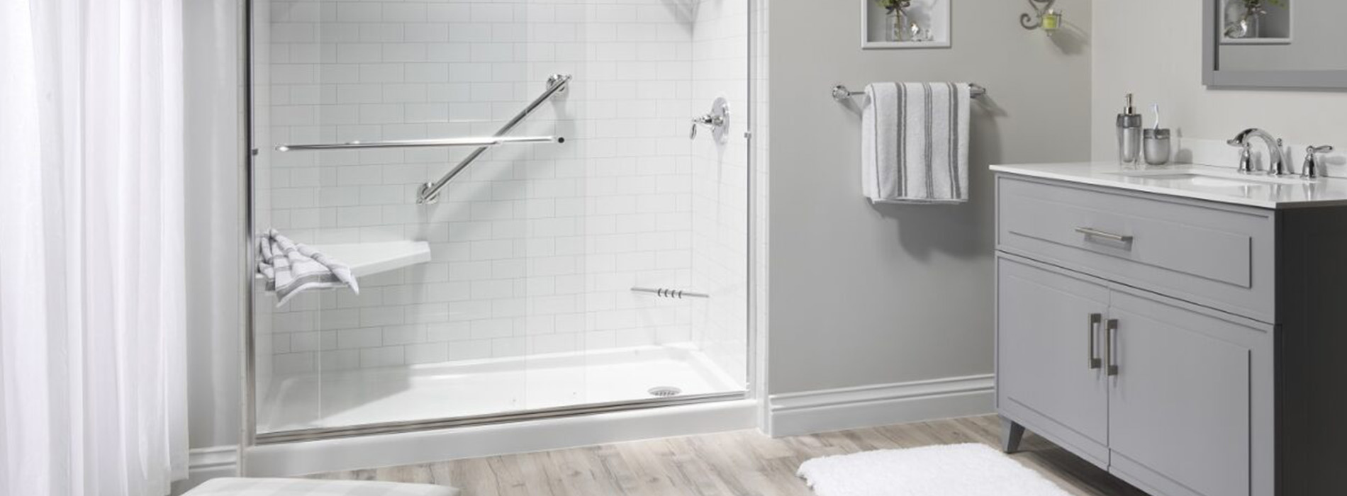 The image shows a modern bathroom with a white bathtub, a shower stall, a toilet, a sink, and a large mirror above the sink.