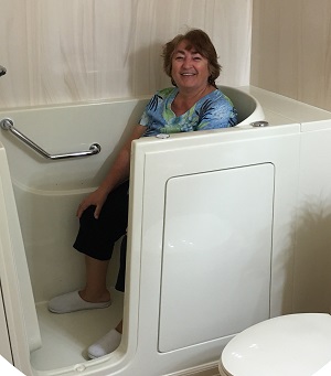 A woman sitting inside a bathtub with her legs crossed, smiling at the camera.