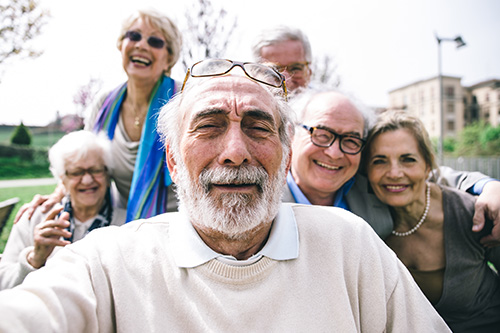 The image depicts a group of elderly people posing for a photograph with smiles on their faces.