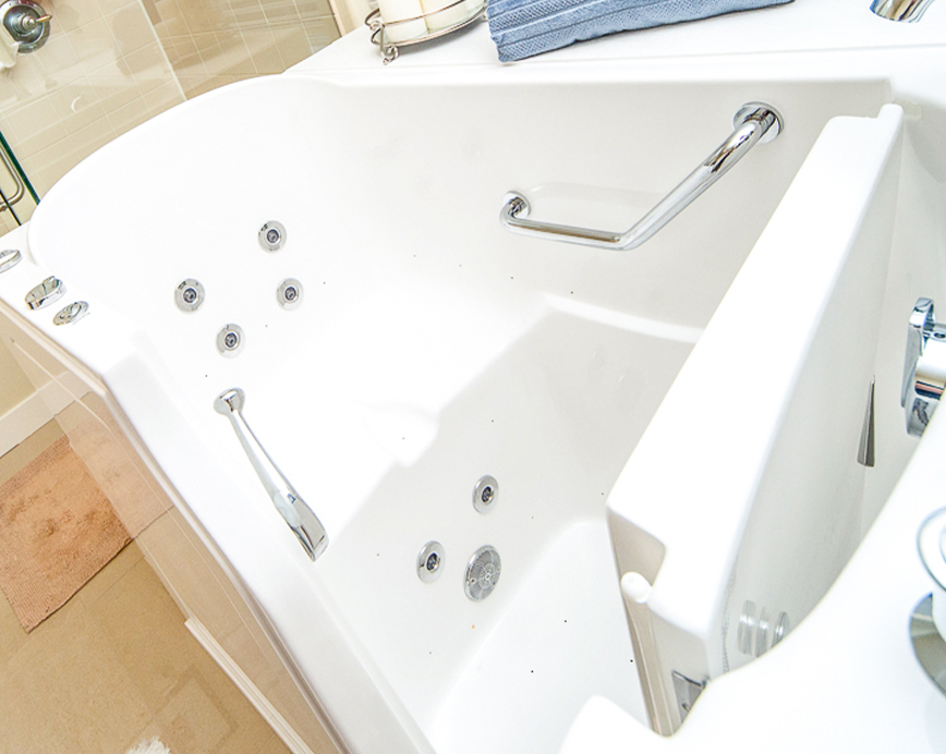 The image shows a modern bathtub with built-in jets and a backrest, set into a bathroom interior with tiled walls and flooring.