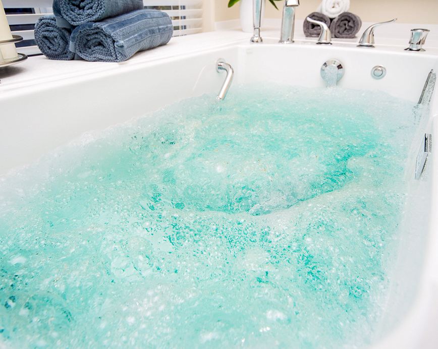 A large bathtub filled with bubbles and water, situated in a bathroom.