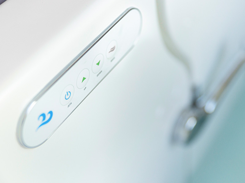The image displays a close-up view of a modern bathroom faucet with a digital interface, showing a water temperature control panel with a blue icon and two buttons on a white background.
