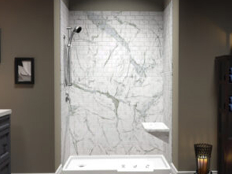 The image shows a modern bathroom interior with a marble-patterned wall, a large shower enclosure with glass doors, a freestanding bathtub, and a sink vanity with a mirror above it.