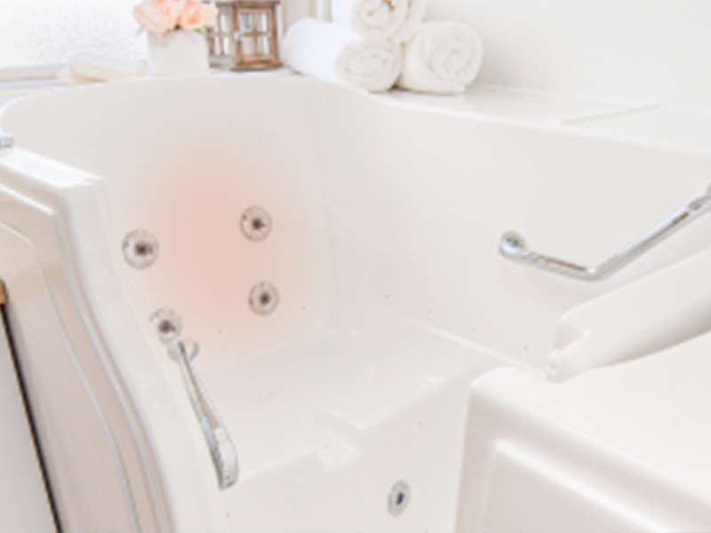 The image shows a modern bathroom interior with a white bathtub, a shower head mounted on the wall above the tub, a chrome faucet, and a clean, minimalist design.