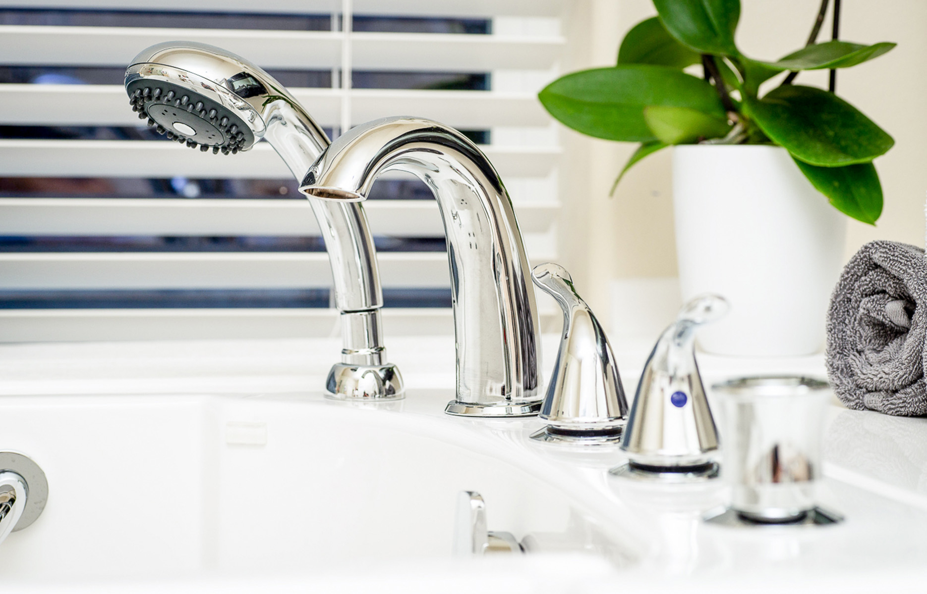 The image displays a modern kitchen sink with a built-in faucet, featuring two handles on either side of the spout.